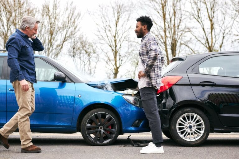 Senior and younger male drivers get out of cars and inspect damage after road traffic accident. Time for a car accident lawyer. Time to call Nicholas Parr Law.