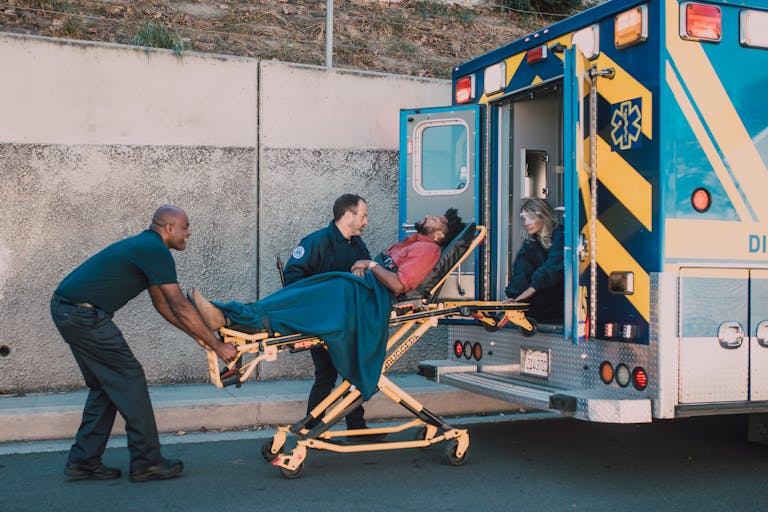 First responders assist an injured man onto a stretcher and into an ambulance during a daytime emergency call. He needs a personal injury lawyer in Baltimore.