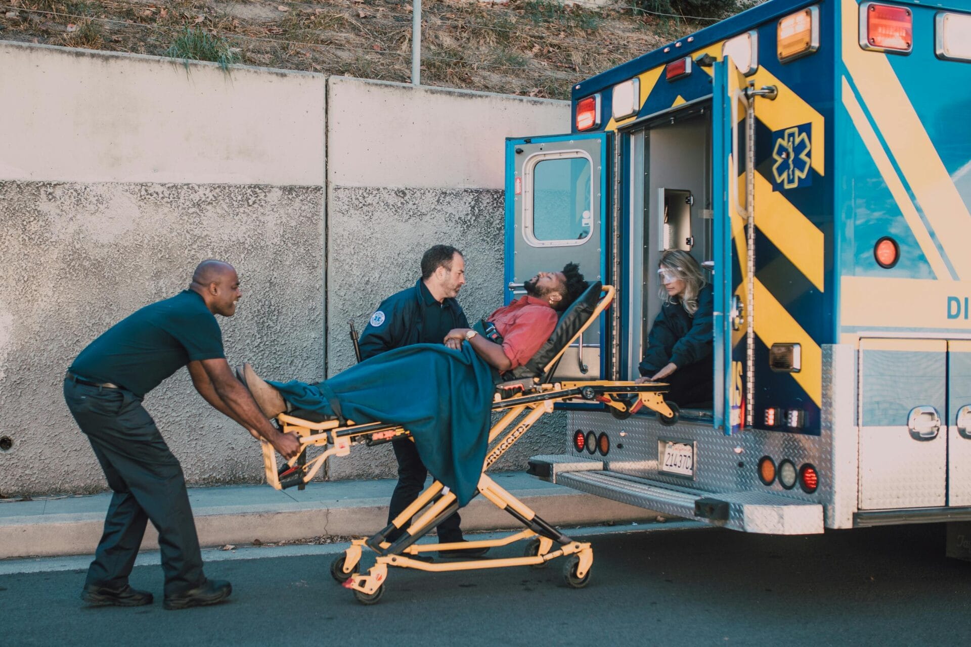 First responders assist an injured man onto a stretcher and into an ambulance during a daytime emergency call. He needs a personal injury lawyer in Baltimore.