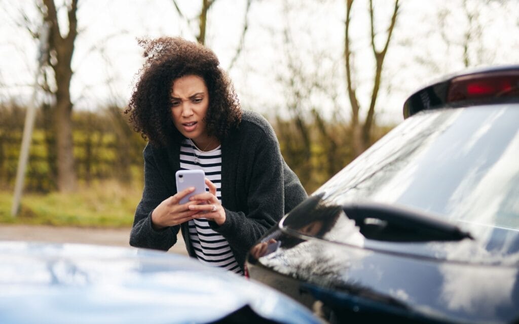 Woman photographing minor uber accident scene with phone.