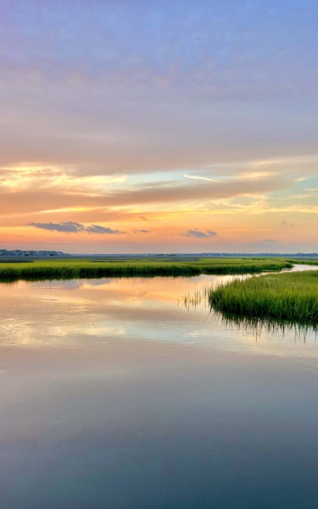 Peaceful sunset over marsh with colorful sky.