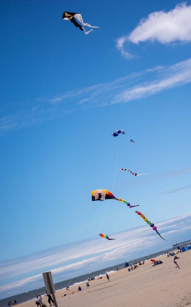 Colorful kites flying above beach in OCean City, MD on sunny day.